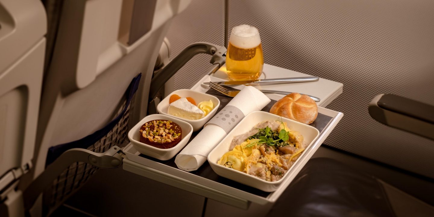 Snack tray with food and beer on an airplane seat.