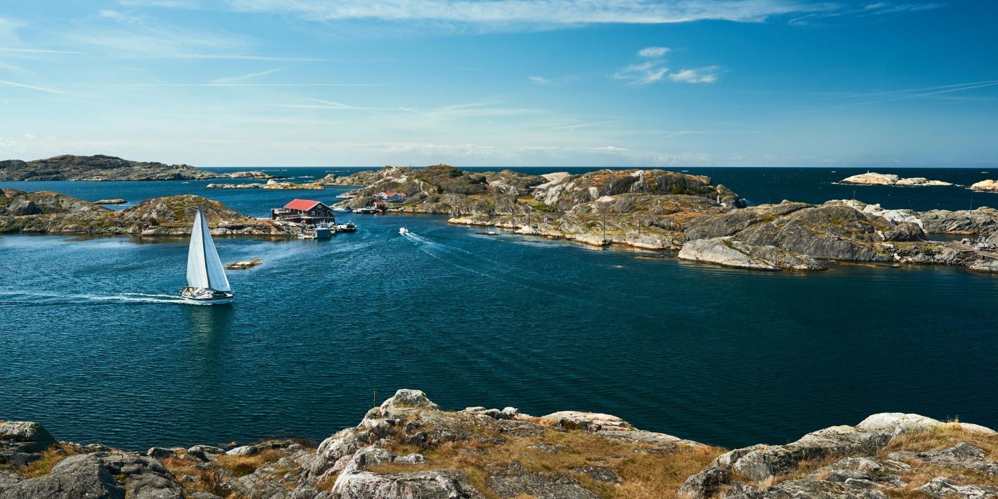 Sea landscape with sailboat and rocky coastline on the South of Sweden. Southern coastline of Sweden with view at sailing-ships and rocky islands.