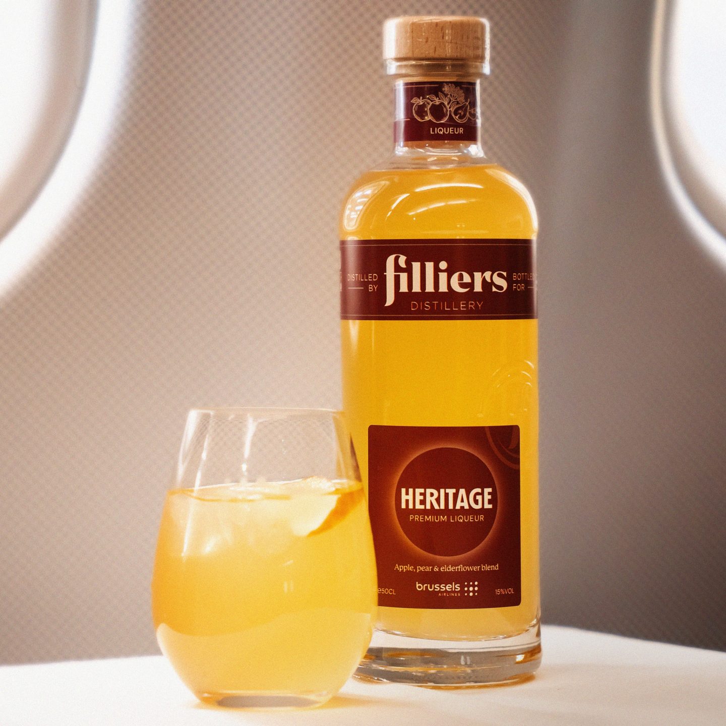 Botella de ginebra Filliers Heritage y un cóctel exclusivo sobre la bandeja de un avión.