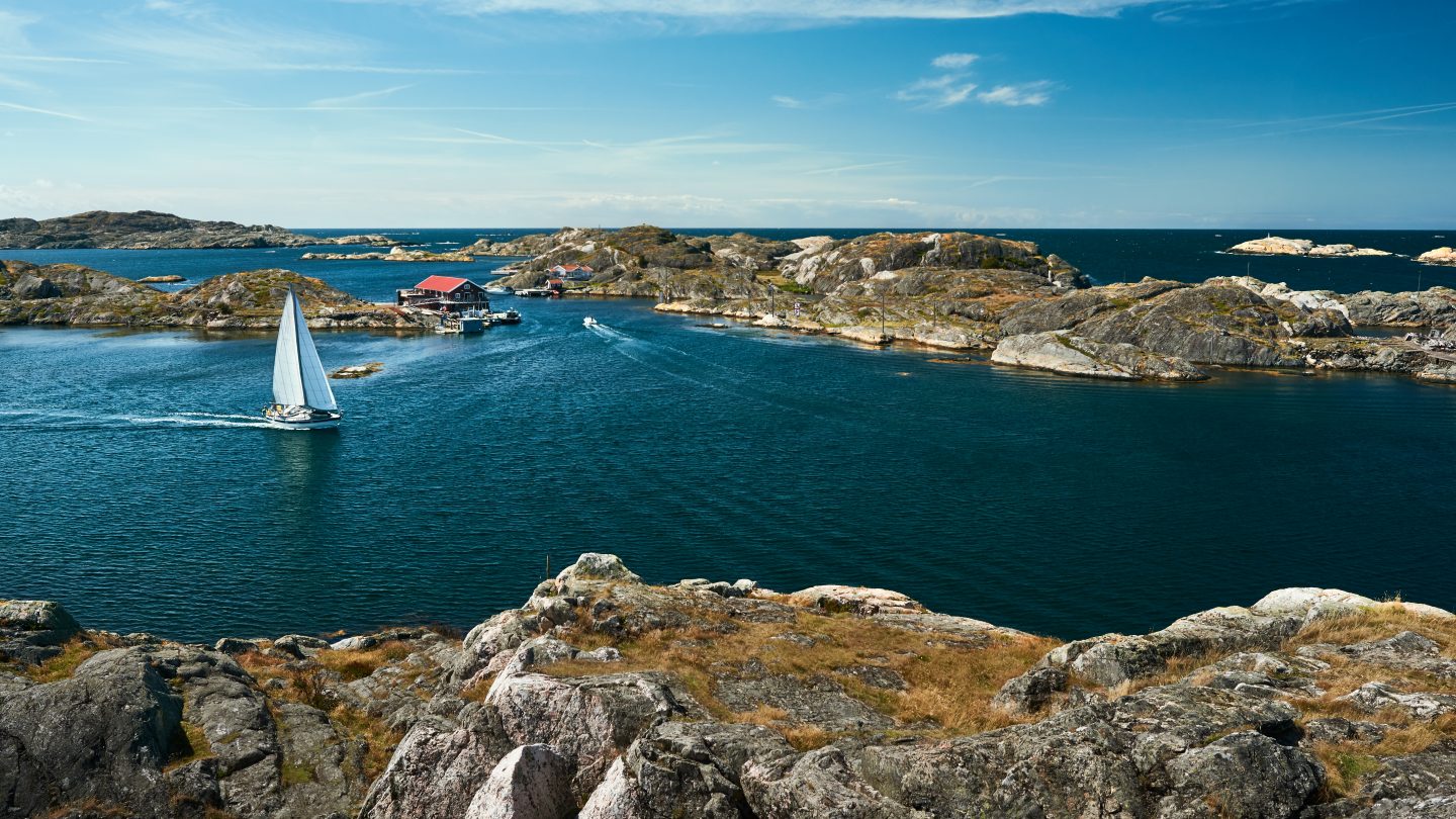Sea landscape with sailboat and rocky coastline on the South of Sweden. Southern coastline of Sweden with view at sailing-ships and rocky islands.