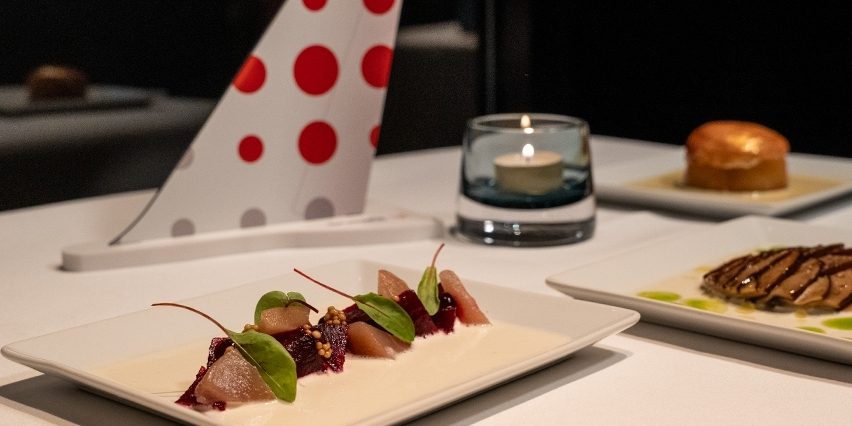 An exclusive Business Class meal with a glass of wine and a dessert onboard.