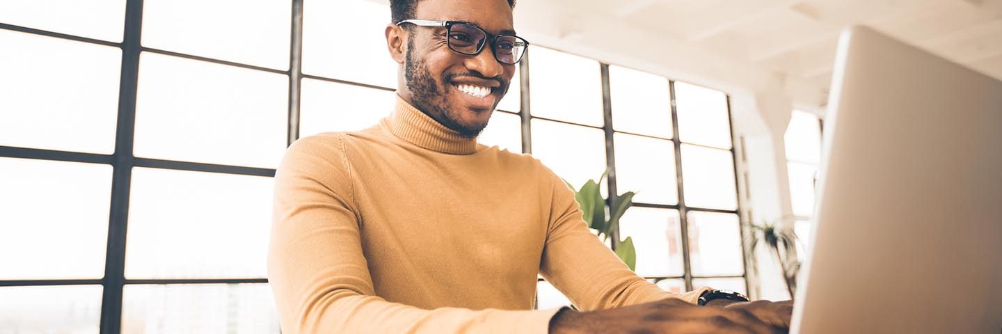 Homme souriant devant son ordinateur portable